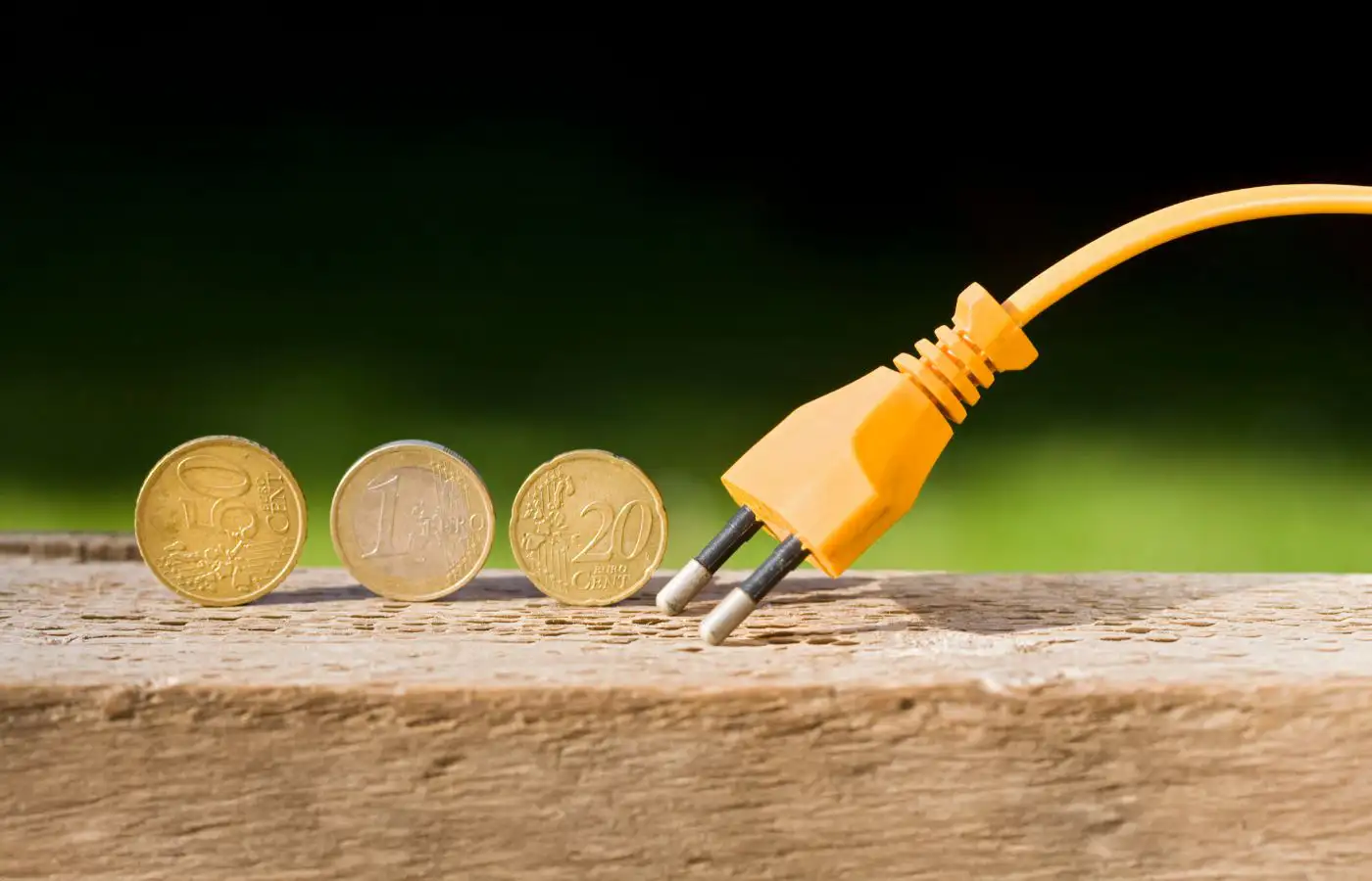 Une prise électrique orange posée à côté de pièces en euros, symbolisant le financement des projets énergétiques et les coûts associés.
