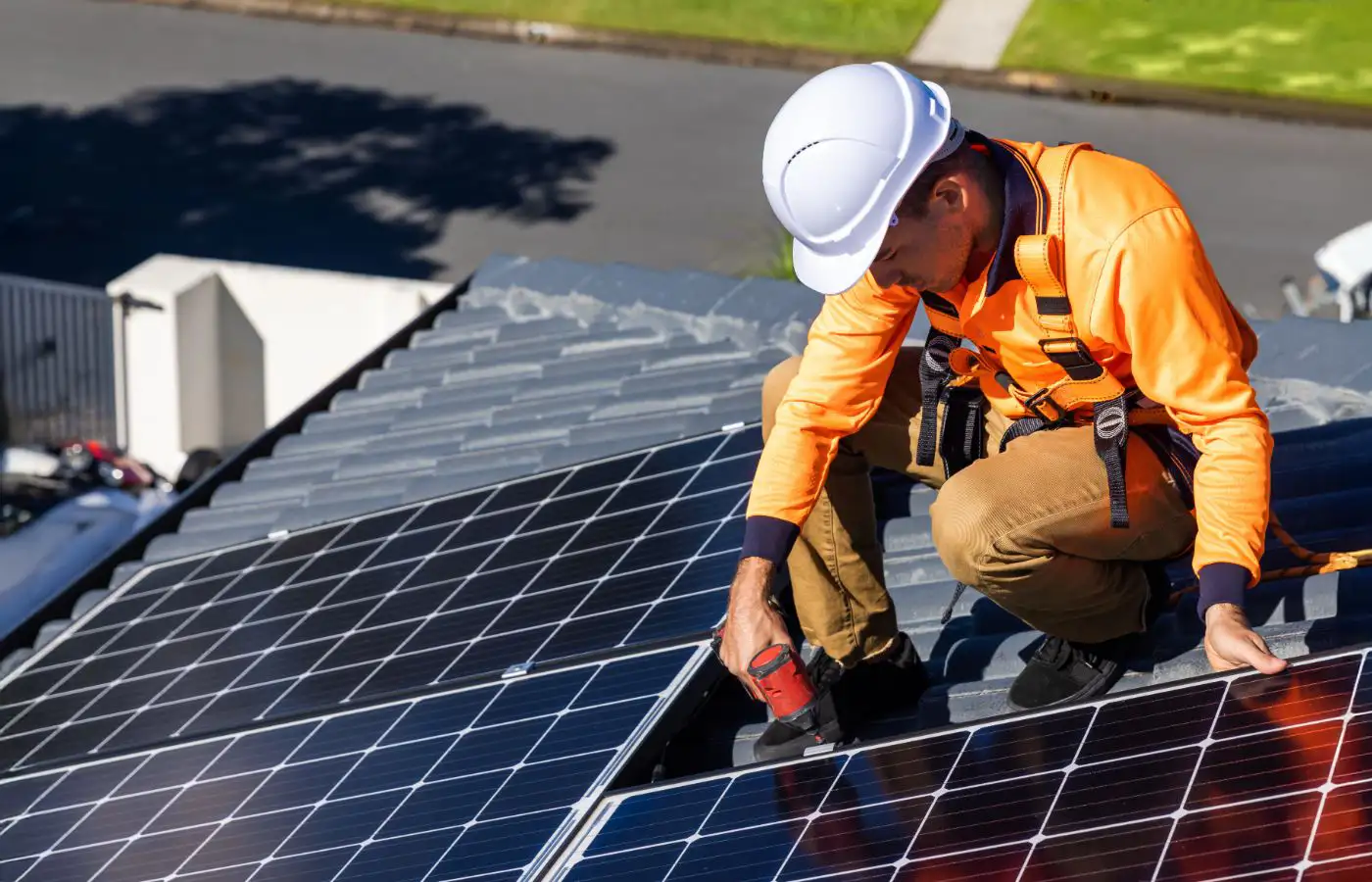 Technicien installant des panneaux solaires sur un toit, illustrant la mise en place d'une infrastructure pour une communauté énergétique durable.