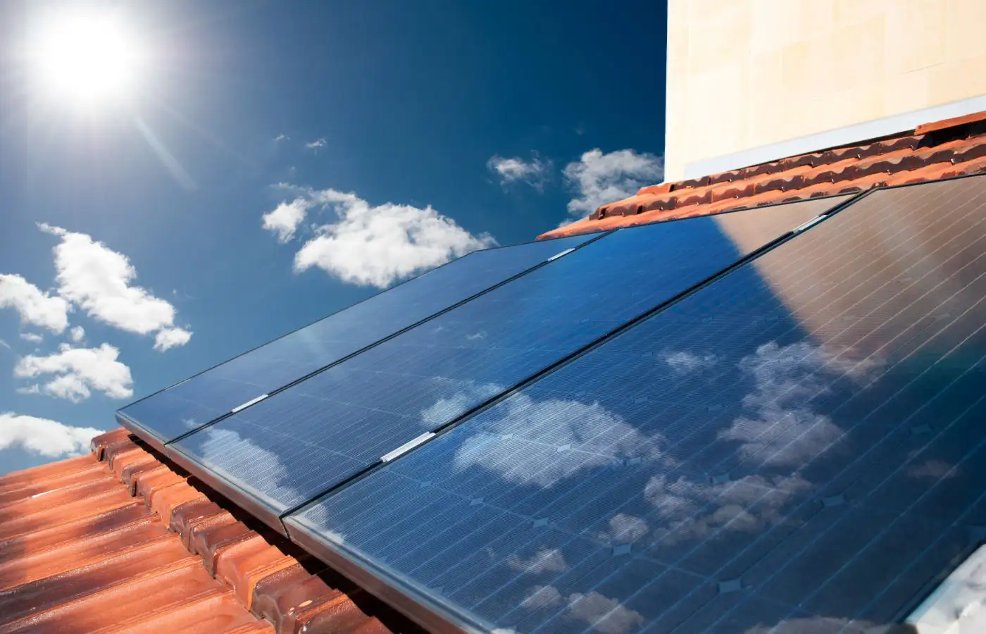 Panneaux solaires sur un toit sous un ciel bleu ensoleillé, symbolisant l'énergie renouvelable et propre pour les communautés énergétiques.
