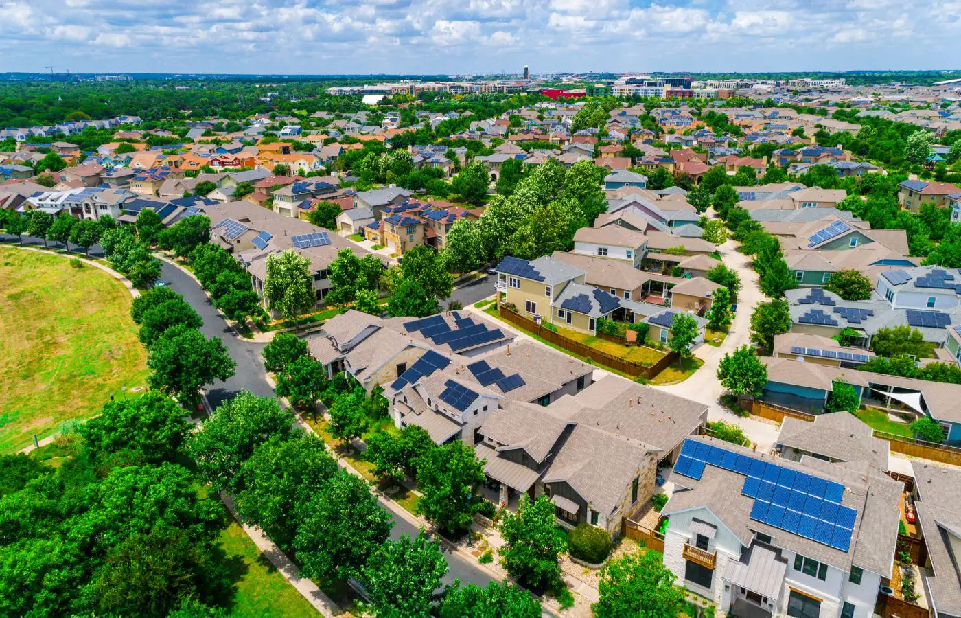 Vue aérienne d'un quartier résidentiel avec des toits équipés de panneaux solaires, illustrant une communauté énergétique durable et locale.